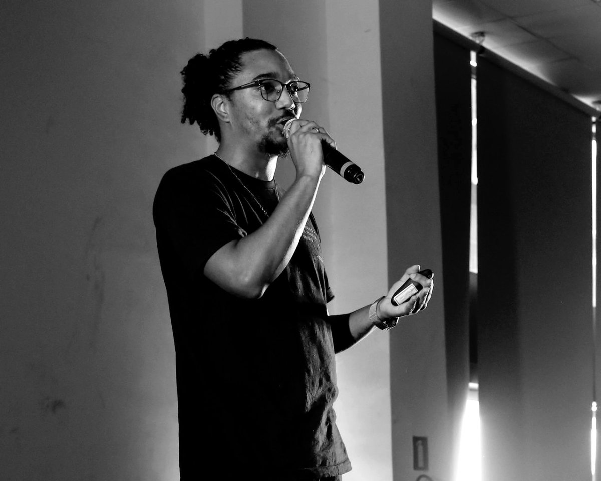 Kayto Beraldo palestrando com microfone, em preto e branco